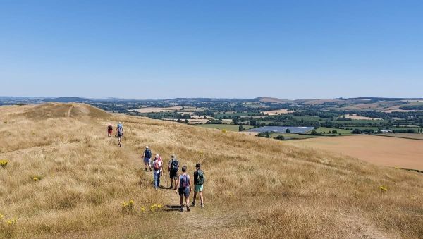 dry grass landscape blue sky and distant hills with figures walking away